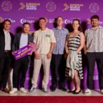 Winners photographed at an awards ceremony backdrop