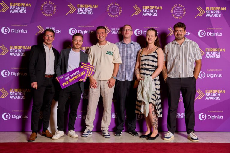 Winners photographed at an awards ceremony backdrop