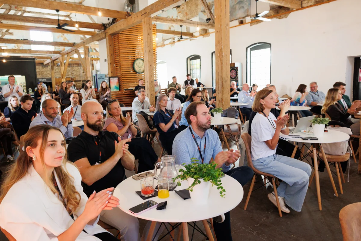 Audience in a timber-beamed loft venue at the Allegro Brand Day in Prague