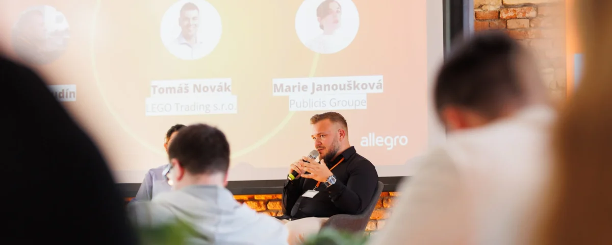 Panel moderator in front of the panel screen at the Allegro Brand Day in Prague
