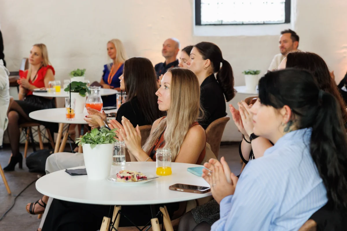 Guests applauding at round tables at the Allegro Brand Day in Prague