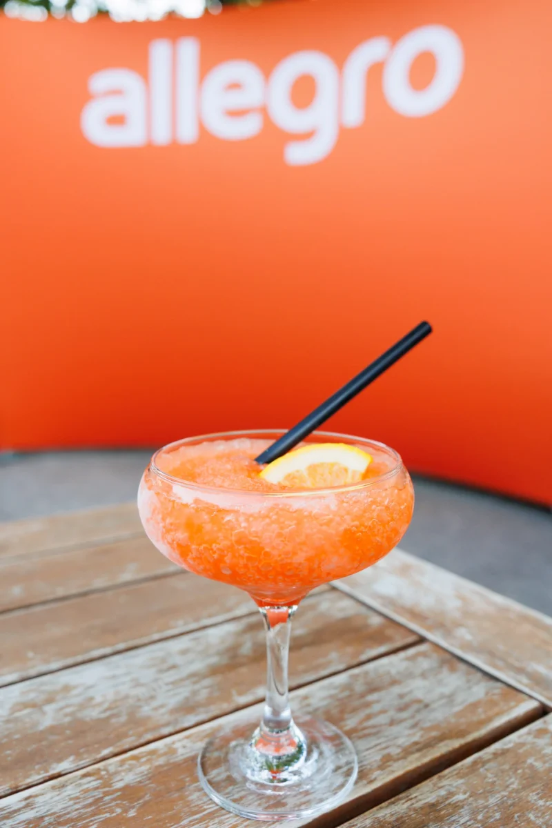 Orange cocktail in front of the Allegro sign at the Allegro Brand Day in Prague