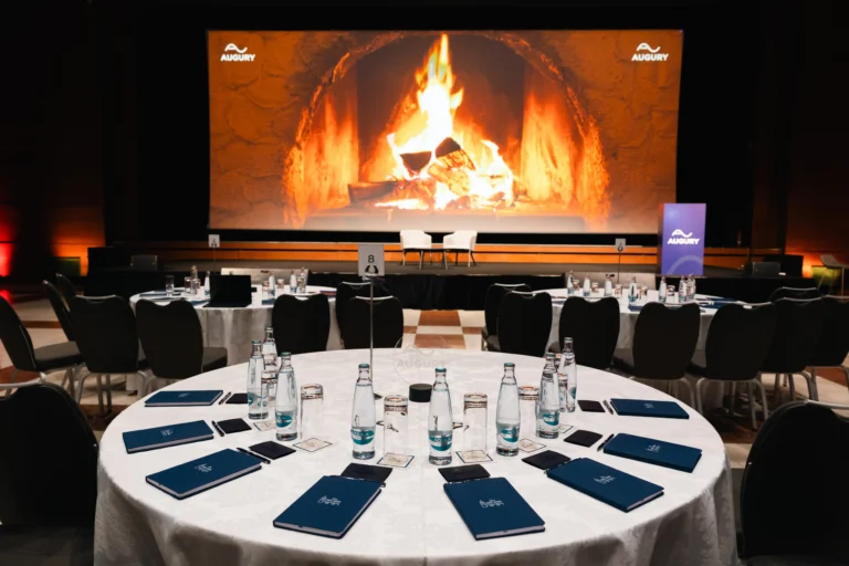 Session room with round tables and a fireplace projection at Hilton Prague Atrium