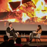Fireside chat on stage in front of a fireplace projection at Hilton Prague Atrium