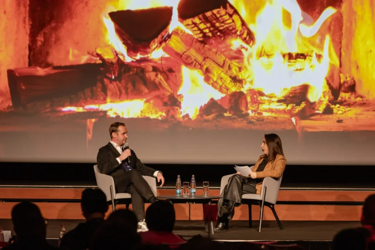 Fireside chat on stage in front of a fireplace projection at Hilton Prague Atrium